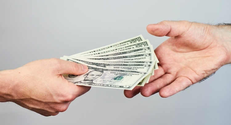 One outstretched hand is giving money to the other outstretched hand.