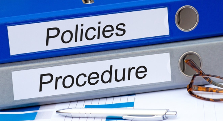 Two binders are labeled as "policies" and "procedures" sit atop one another.