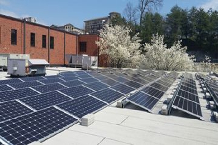 Solar panels are slanted atop a roof soaking in the sun.
